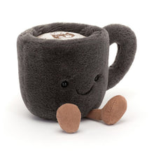 A plush toy resembling a chocolate coffee cup with a happy facial expression, complete with a handle and nutmeg cord feet.