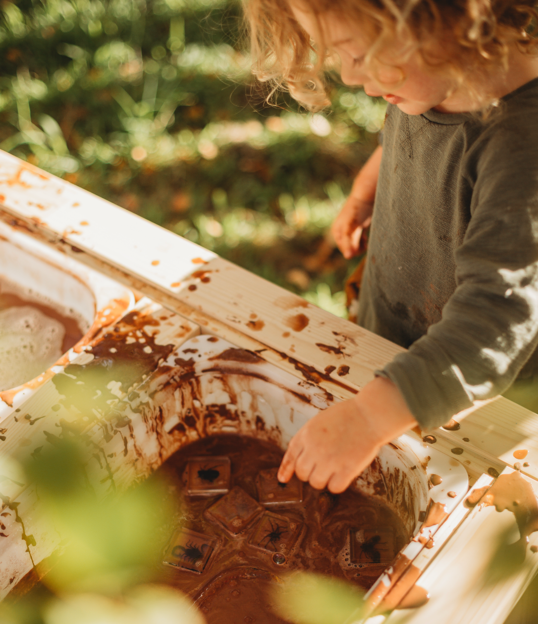 Two children playing with a resin bug specimen set in a natural setting