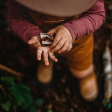 Person holding a small object in their hands with a blurred natural background