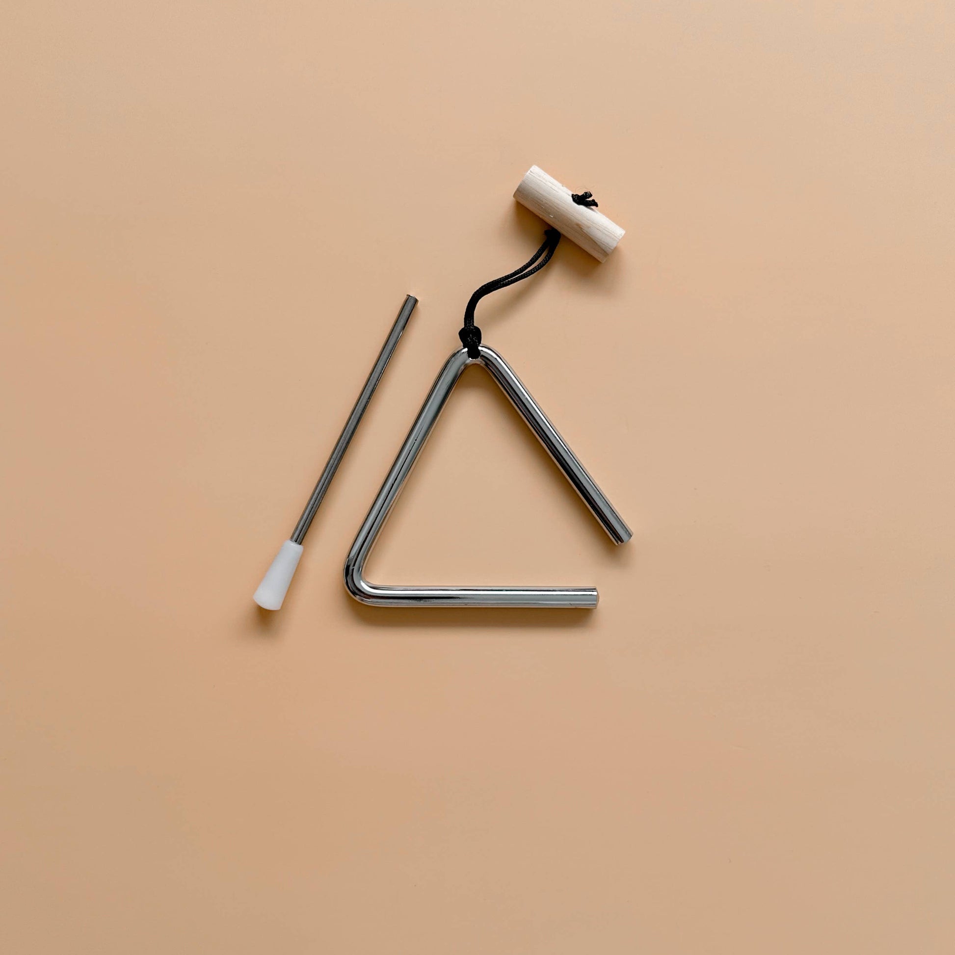 Love Note Co mini triangle musical toy with striker on a warm beige background.