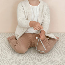 Child seated on a patterned rug playing the Love Note Co mini triangle musical toy.