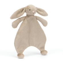 A beige colored plush toy in the shape of a bunny with long lop ears, a pink suedette nose, and embroidered eyes. The toy has a soft, un-stuffed body and bobble feet.