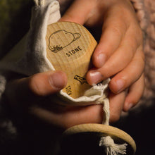 Hand holding a wooden die with branding, wrapped in a cloth pouch.