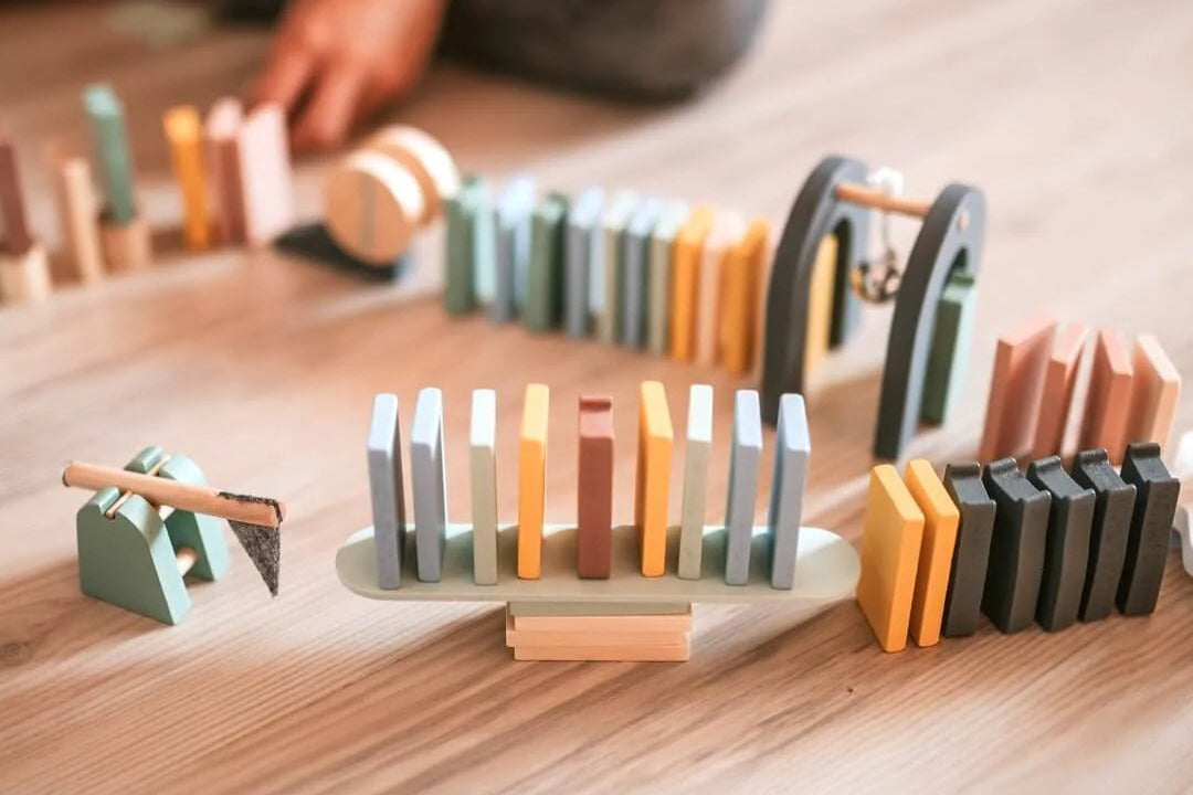 Colorful wooden toy set on a wooden floor with a child's hand interacting with it.