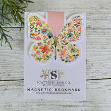 A floral patterned magnetic bookmark with a butterfly design, displayed on a white background with a wooden texture.