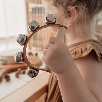 Close-up of a child playing the Love Note Co handbells in a neutral nursery.