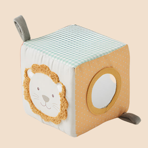A soft fabric activity cube for babies. A round baby-safe mirror on one side and a friendly lion face.