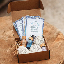 A Moon Magic Mindful Potion Kit displayed in an open cardboard box, containing various small bottles, jars, and cards with affirmations.