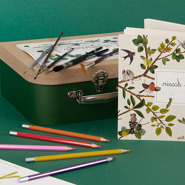 Art supplies including colored pencils, a green box, and a card with nature-themed design on a green background.