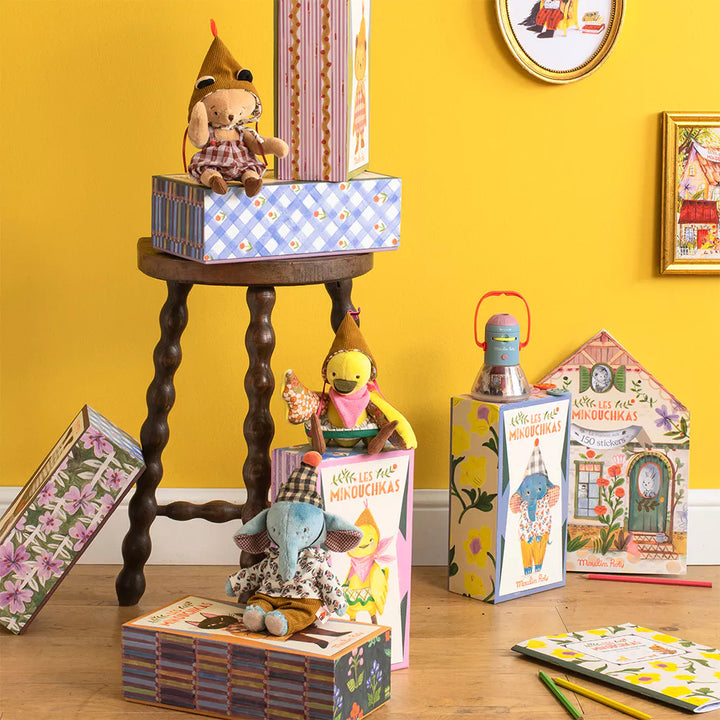 Colorful children's toys and books on a wooden floor against a yellow wall.