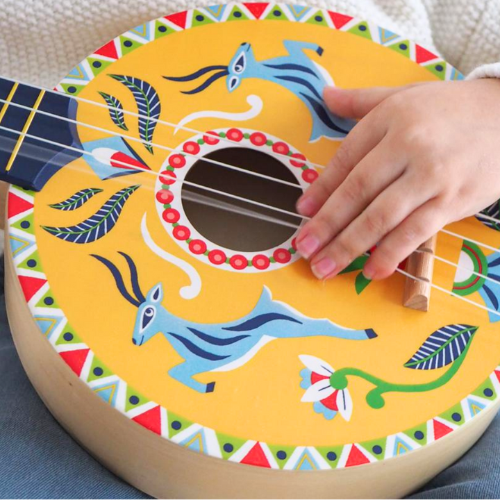 Colorful children's ukulele with hand playing it on a light background