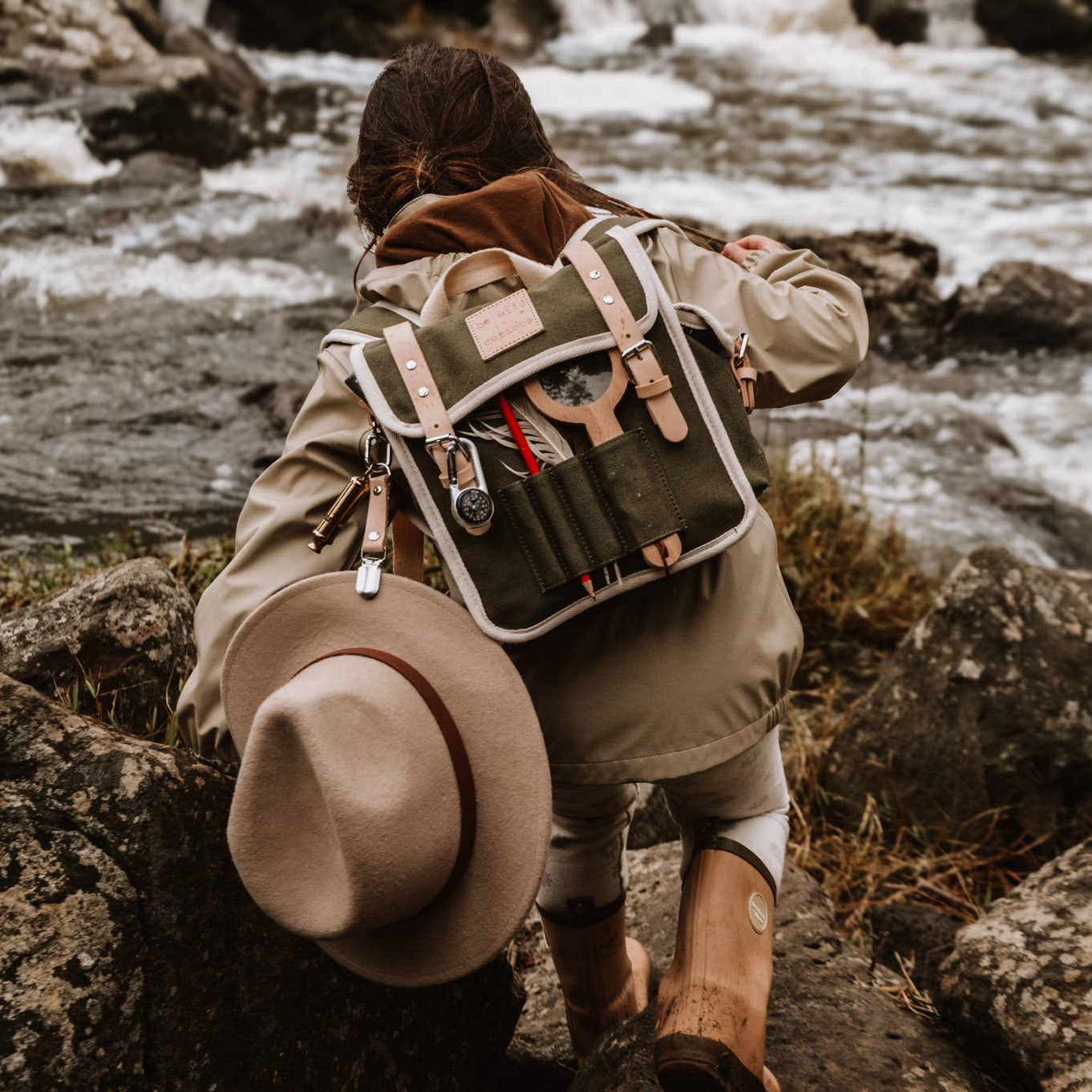Child with a nature backpack hiking near a river