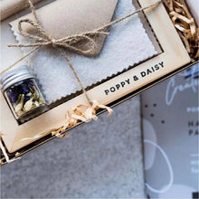 A Handmade Paper Kit by Poppy & Daisy, featuring a box with various crafting materials such as a wooden mould, deckle, aluminum mesh, glass jar of dried flowers, rolling pin, cotton sheets, felt sheet, and recycled envelopes.