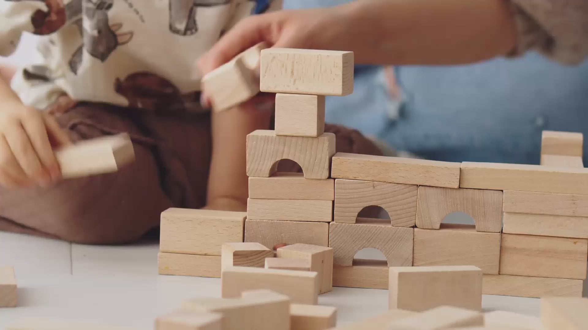 载入视频： Child and parent settling on the floor playing with a natural wooden block set