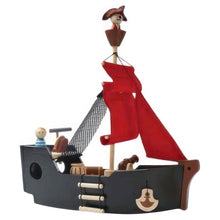 A wooden pirate ship toy with a red sail, including figures of a pirate and a prisoner, a crew member, a treasure chest, a cannon, a ladder, and a small boat.
