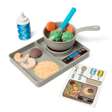 Toy kitchen set with cooking pan, tray, and toy food items on a white background