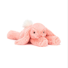 A plush toy resembling a lop-eared bunny in bright apricot fur with a fluffy cream bobtail.