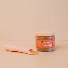 Jar of 'tiny tummies' pretend play baby food with a spoon on a beige background