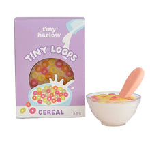 Box of tiny harlow Tiny Loops cereal with a bowl of cereal and spoon on a light background
