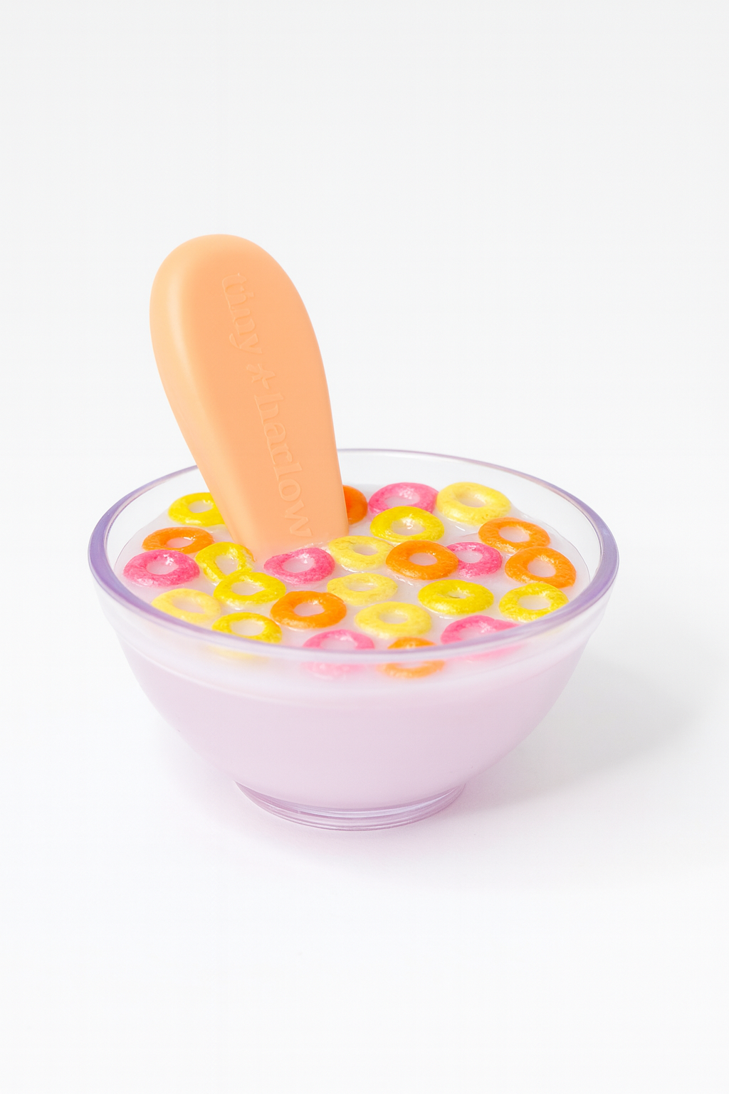 Plastic bowl with colorful  pretend cereal and a spoon on a white background