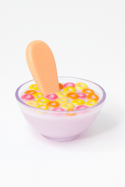 Plastic bowl with colorful  pretend cereal and a spoon on a white background