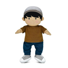 A soft organic doll with a caramel color shirt, blue pants, and gray hat, detailed with embroidered facial features and removable clothes.