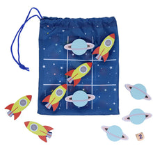 A travel game set with wooden rockets and planets, including a blue pouch with a rocket design and a die, and several wooden counters on a white background.