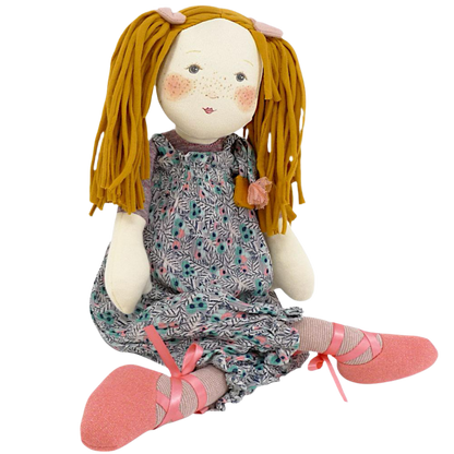 Rag doll with blonde pigtails and floral bloomers on a plain background