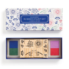A William Morris classic floral rubber stamp set displayed alongside its packaging which features floral patterns. The set includes multiple stamps with floral and animal designs and four colored ink pads.