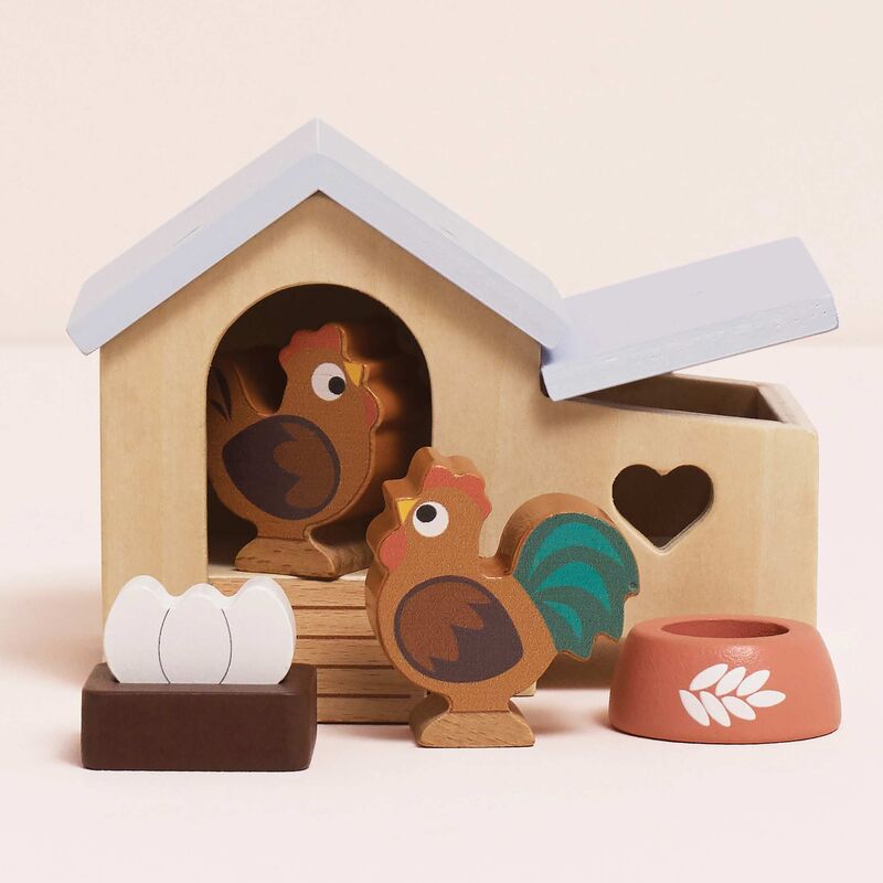 Wooden toy set with a chicken coop, chickens, and an egg on a beige background