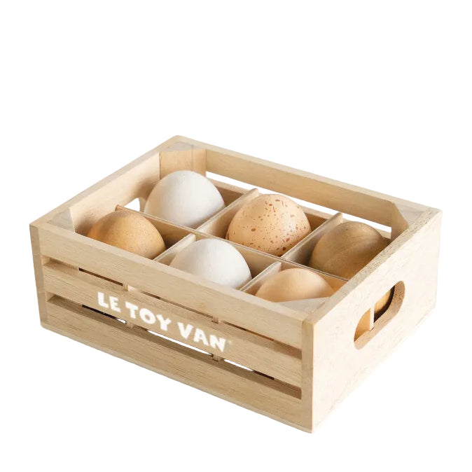 Wooden crate with compartments containing wood eggs labeled 'Le Toy Van' on a white background