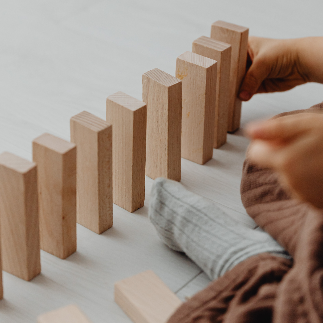 Hand setting wooden blocks in a row on a light surface