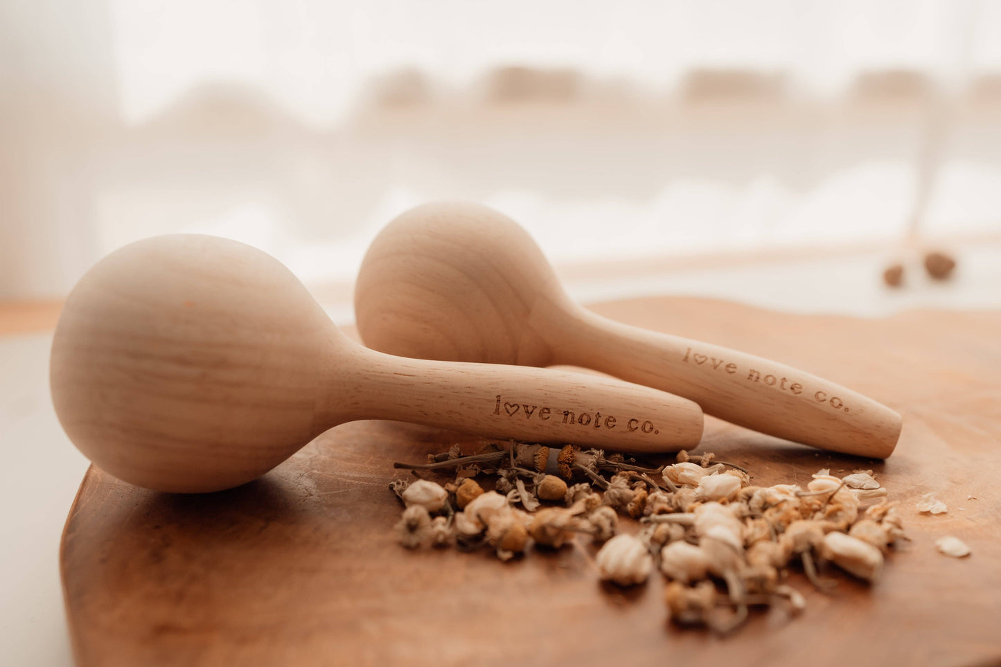 Love Note Co wooden maracas styled on a timber board with dried botanicals.