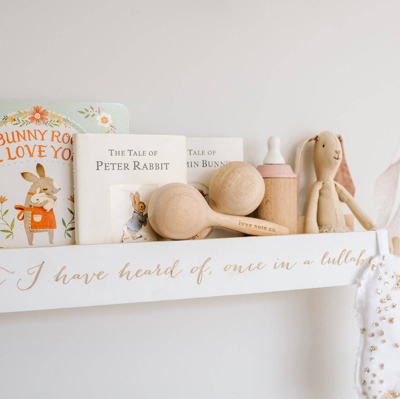 Love Note Co wooden maracas displayed among classic toys and books on a nursery shelf.
