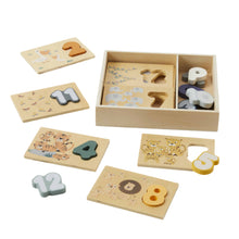 A wooden number sorter puzzle with various numbers and animal pictures on the pieces, displayed both inside a beige box and scattered outside.