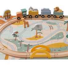 A wooden train set with animal puzzle pieces, including representations of an elephant and a giraffe, on a green landscape with a bridge.
