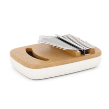 A white and natural wood kalimba musical instrument with metal note bars, on a white background