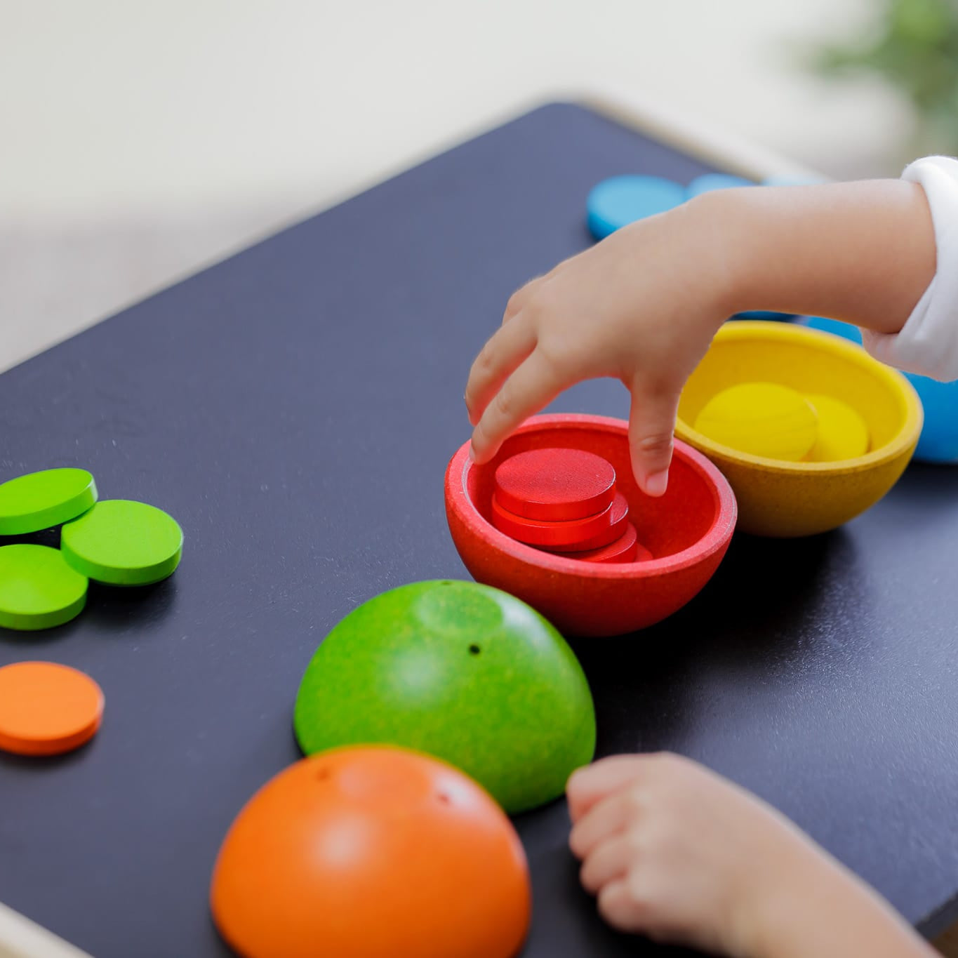 Child playing with colorful wooden toys on a dark surface