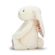 A white bunny plush toy with floral fabric accents on the foot and ear, pictured on a white background.