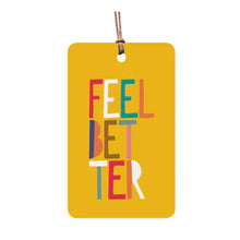 A yellow gift tag with the text 'FEEL BETTER' in a colorful design, featuring rounded edges and a natural hemp cord attached.