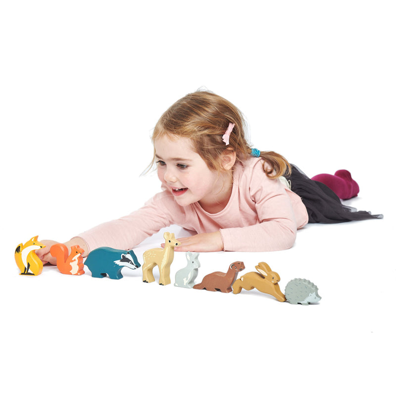 Young girl playing with 8 wooden woodland theme animal figures