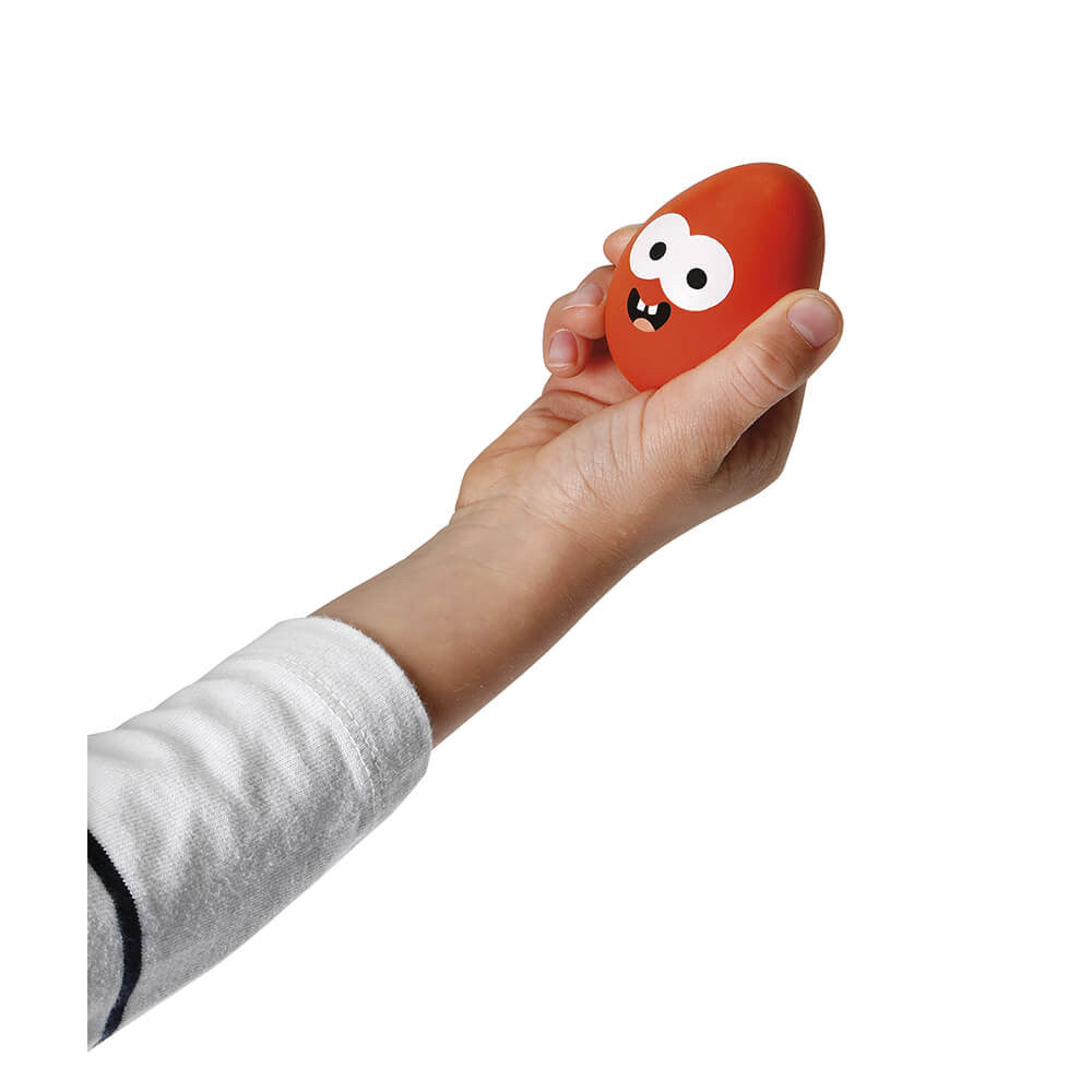 Child's hand holding a red egg with a quirky painted face.