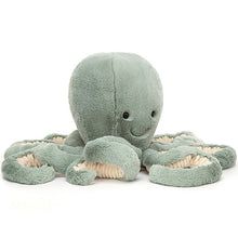 A large sea moss green plush octopus toy with bright, glossy eyes and long curly tentacle arms.