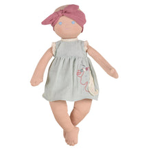 An organic cotton baby doll with a weighted bottom, wearing a green dress and a pink headscarf.
